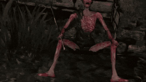 a bloody monster is sitting on the ground holding a sword in a dark room .