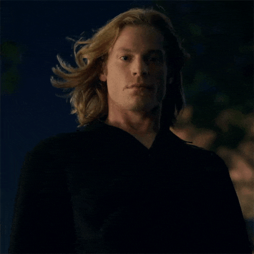 a man with long blonde hair wearing a black jacket