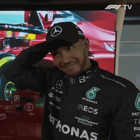 a man wearing a petronas hat stands in front of a screen