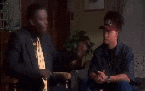 two men are sitting on a couch in a living room .