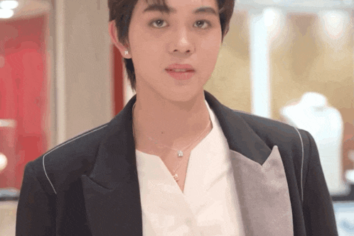 a young man wearing a black jacket and a white shirt is looking at the camera
