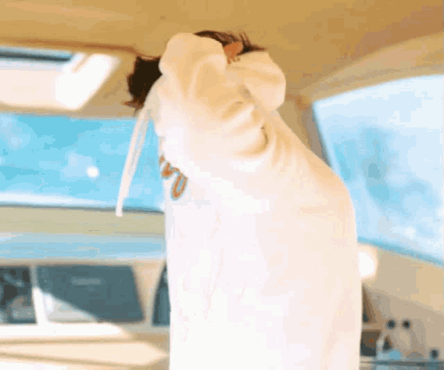 a woman in a white robe is standing in front of a large window