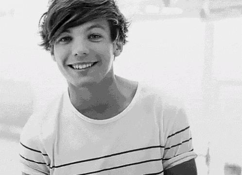 a black and white photo of a young man wearing a striped shirt smiling .