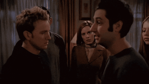 a man in a black shirt is talking to a woman in a dark room