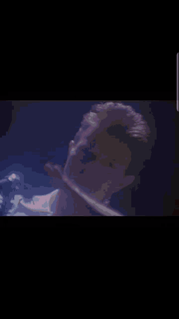 a close up of a man 's face in a dark room with a blue light behind him .