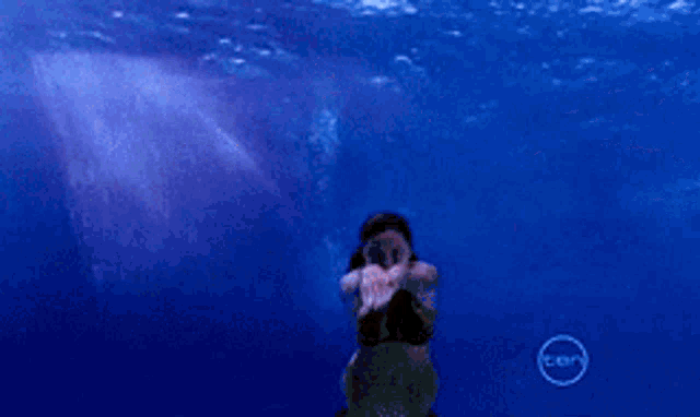 a woman is swimming in the ocean with a cnn logo behind her