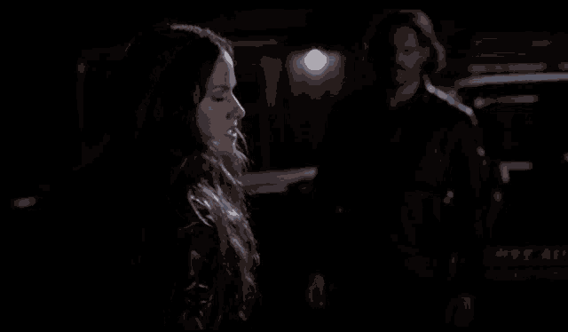 a woman with long hair is sitting in a dark room and looking at the camera .