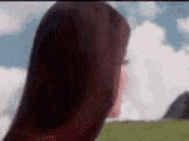 a woman with long red hair is standing in a field .