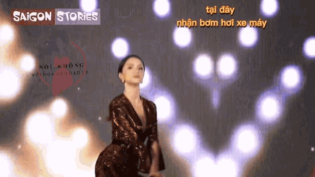 a woman in a sequined dress is dancing in front of a saigon stories sign
