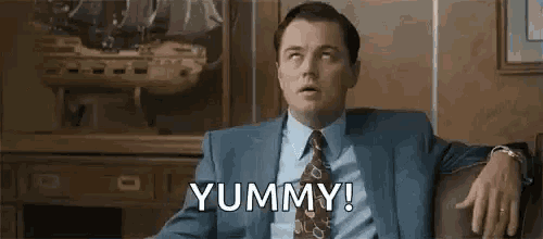 a man in a suit and tie is sitting in a chair with his hands on his hips .