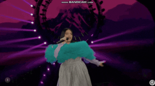 a woman singing into a microphone with a purple background and the words www.bandicam.com on the bottom