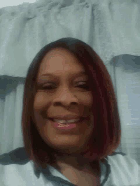 a woman with red hair is smiling for the camera in front of a window .
