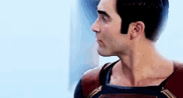 a man in a superhero costume is standing in front of a blue wall .