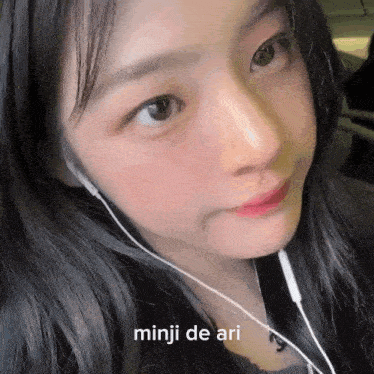 a close up of a girl wearing ear buds with minji de ari written below her