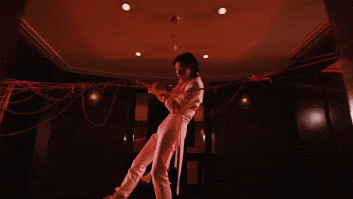 a man in a white shirt and white pants is tied up with red ropes .