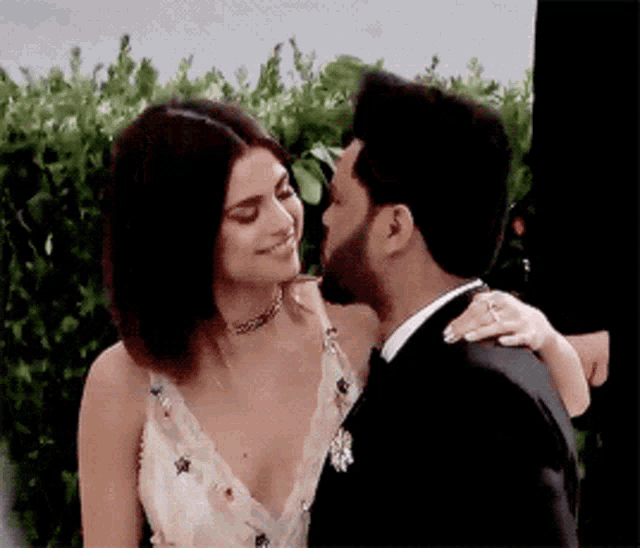 a man in a tuxedo and a woman in a dress are kissing