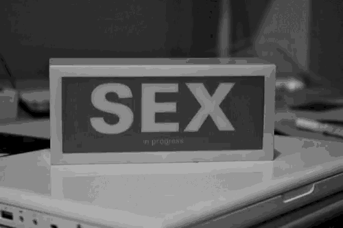a sign that says sex in progress is on top of a laptop