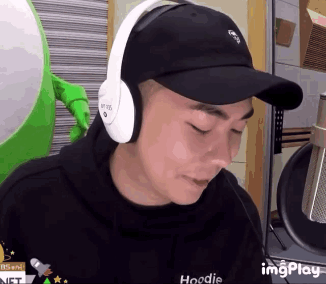 a man wearing a black hat and white headphones with a hoodie that says hoodie on it