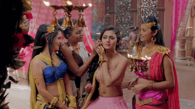 a woman in a pink dress is surrounded by three other women