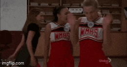 a cheerleader is dancing in a room with shelves and a white board .
