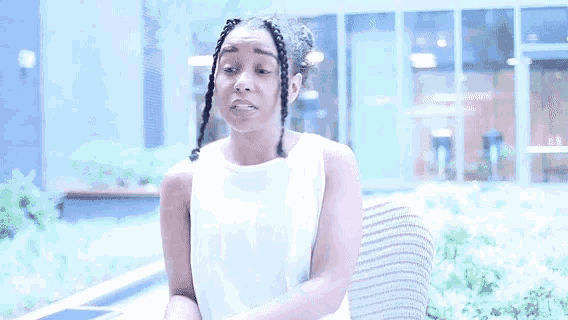a woman in a white tank top is sitting on a couch .