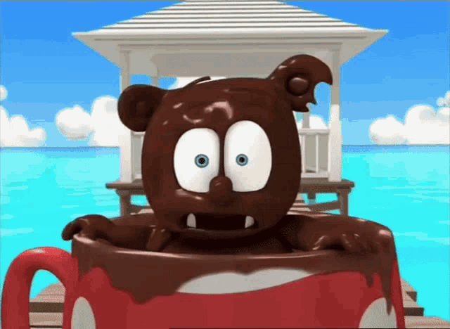 a cartoon gummy bear is sitting in a cup of chocolate