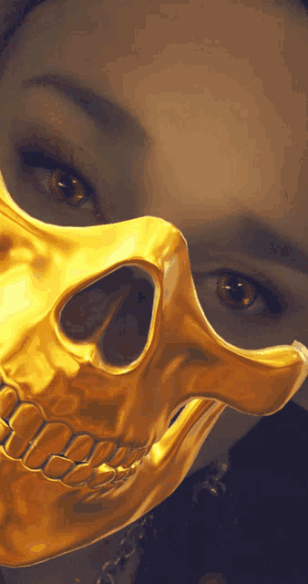 a woman is wearing a gold skull mask