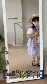a little girl is standing in front of a full length mirror