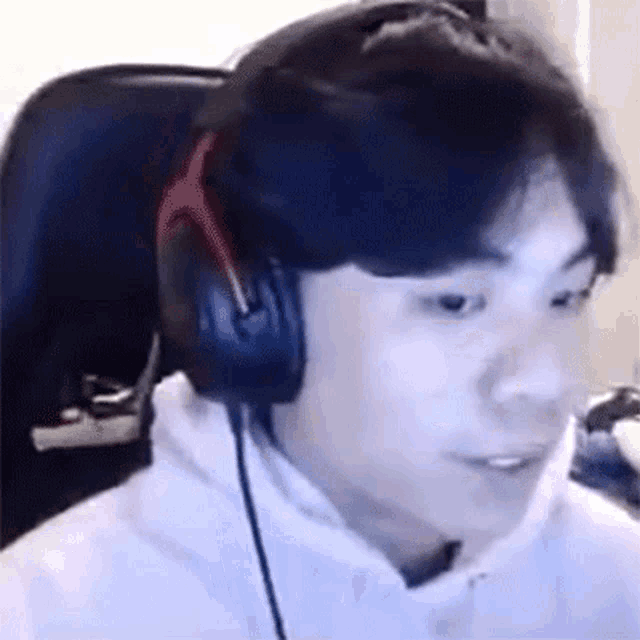 a man wearing headphones and a white hoodie is sitting in a chair .