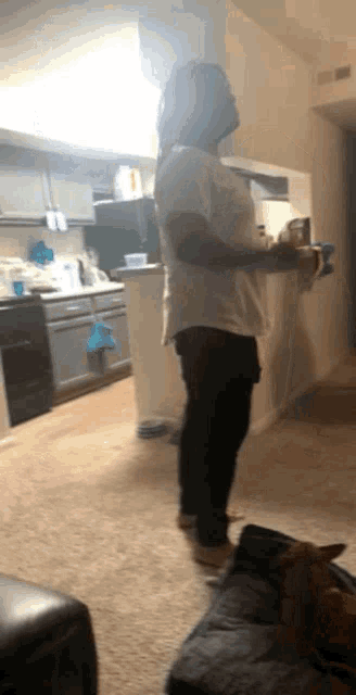 a man in a white shirt is standing in a living room holding a hammer