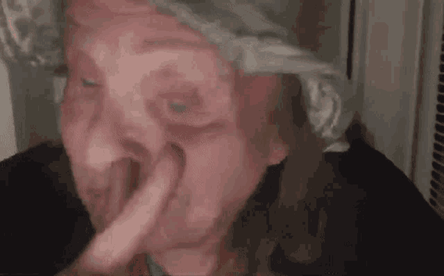 a close up of a person holding their nose with their finger .