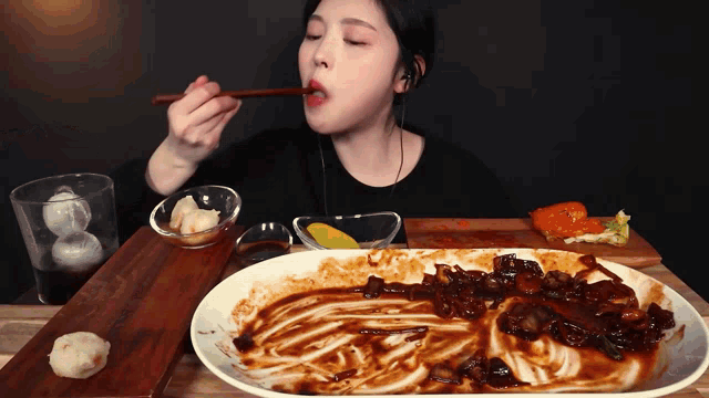 a woman with chopsticks is eating a plate of food