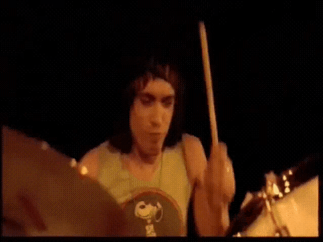 a man in a snoopy shirt playing drums