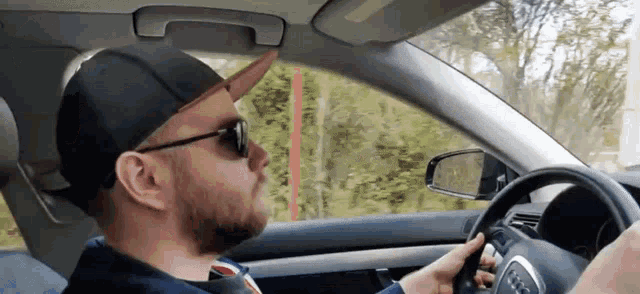 a man wearing sunglasses and a hat is driving an audi