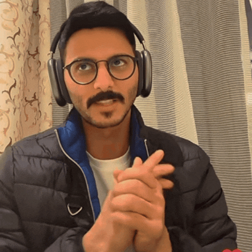 a man wearing headphones and glasses looks at the camera