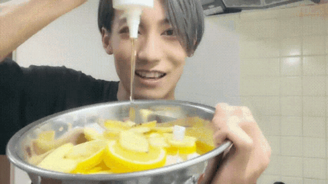 a young man is pouring sauce into a bowl of lemons