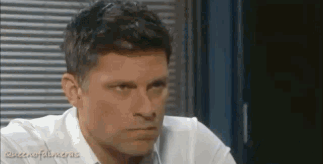 a man in a white shirt and tie is looking at the camera and making a funny face .