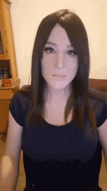 a woman wearing a black shirt and a wig looks at the camera