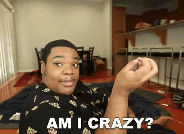a man is laying on the floor holding something in his hand and saying am i crazy .