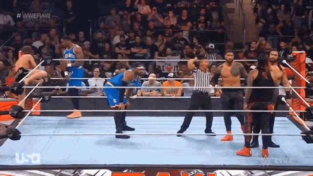 a group of wrestlers are in a wrestling ring with a referee in front of a crowd that is watching
