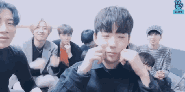 a group of young men are sitting in a room and one of them is making a funny face