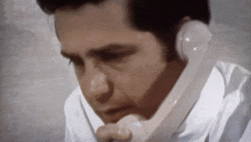 a man in a striped shirt is talking on a white phone