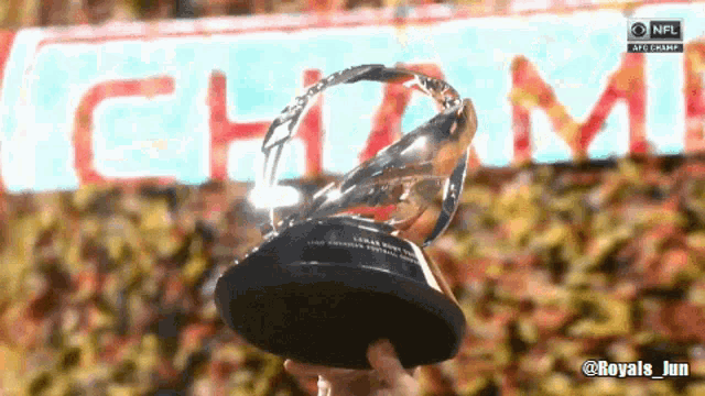 a person holding a trophy in front of a nfl logo