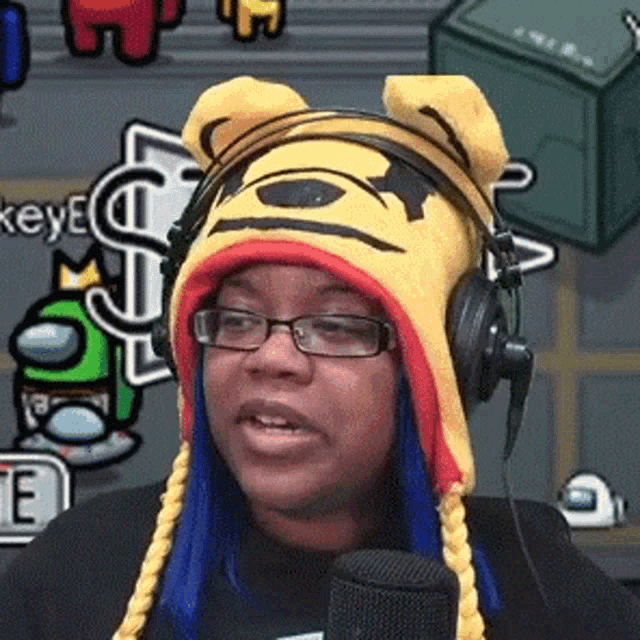 a woman wearing glasses and a winnie the pooh hat is talking into a microphone .