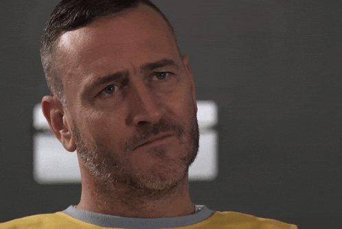 a man with a beard and a yellow shirt looks at the camera