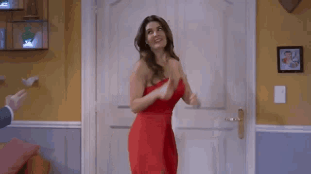 a woman in a red dress is standing in a doorway .