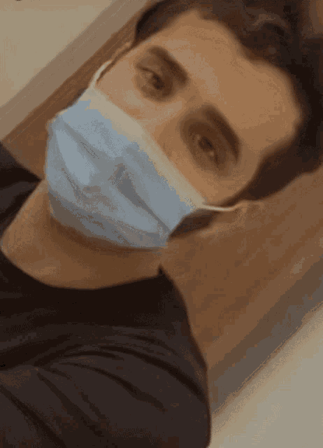 a man wearing a blue face mask is looking at the camera