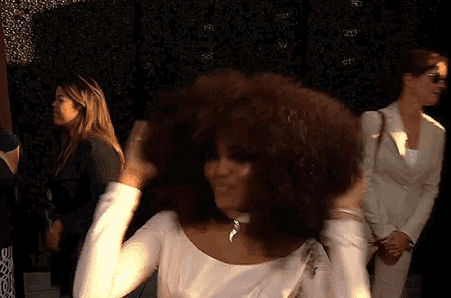a woman with a large afro is standing in a crowd