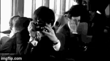 a man is taking a picture of a group of people on a bus in a black and white photo .