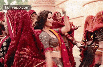 a woman is dancing in front of a crowd of people in red dresses .